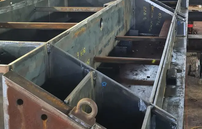 Section of the new Charlestown Harbour lock gate under construction inside a workshop, showing the large steel framework being fabricated
