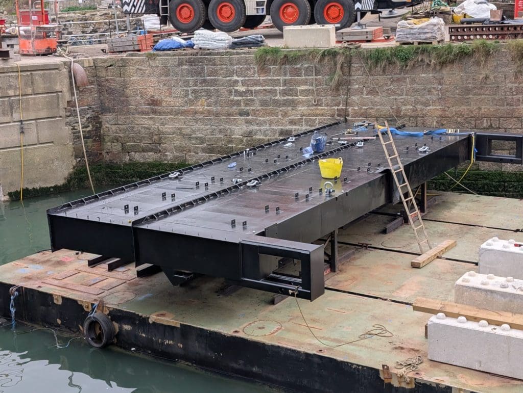Two sections of the enormous steel lock gate are bolted together on a floating pontoon ready to be installed. 